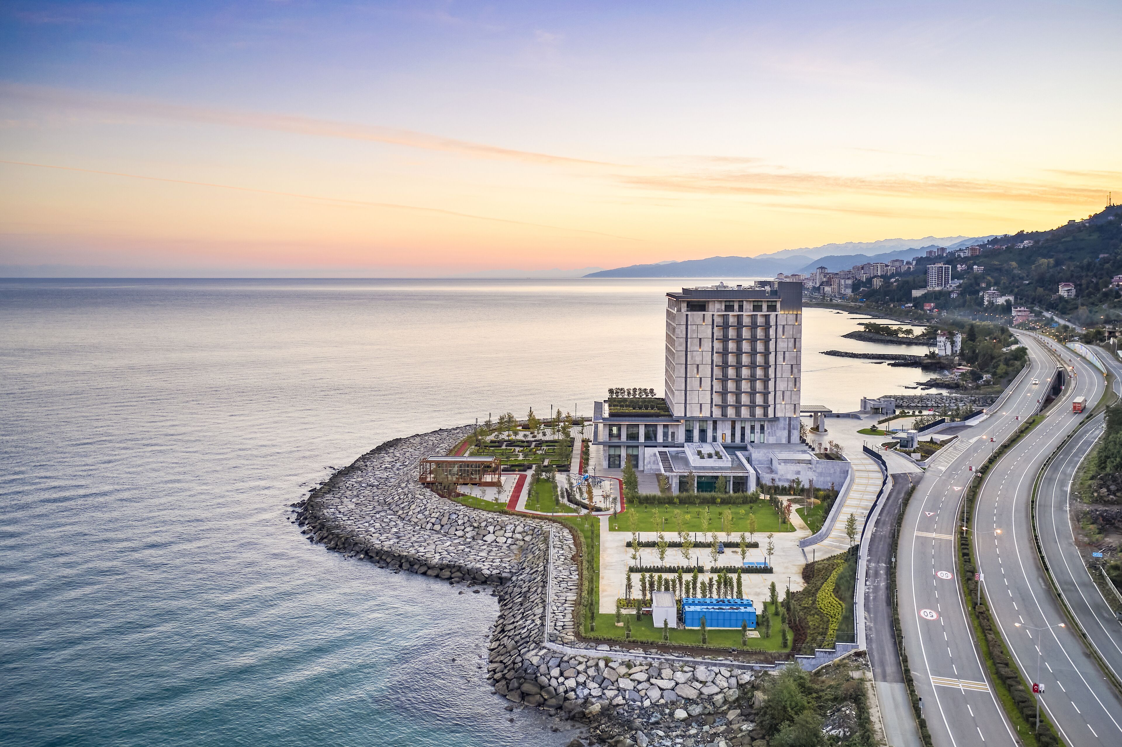 Un hotel moderno con vistas al mar, un estacionamiento y una carretera.
