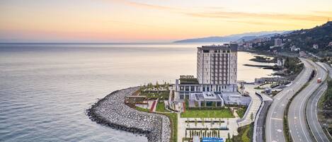 Un hotel moderno con vistas al mar, un estacionamiento y una carretera.