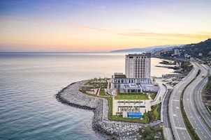 Un hotel moderno con vistas al mar, un estacionamiento y una carretera.