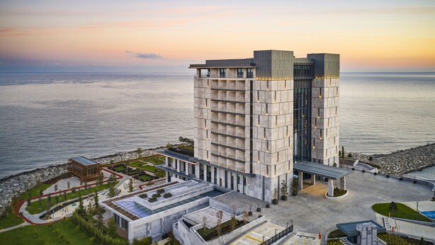 A modern hotel with a unique architectural design, featuring a prominent central tower and a spacious courtyard. - Ricosta Hotel (Rize)