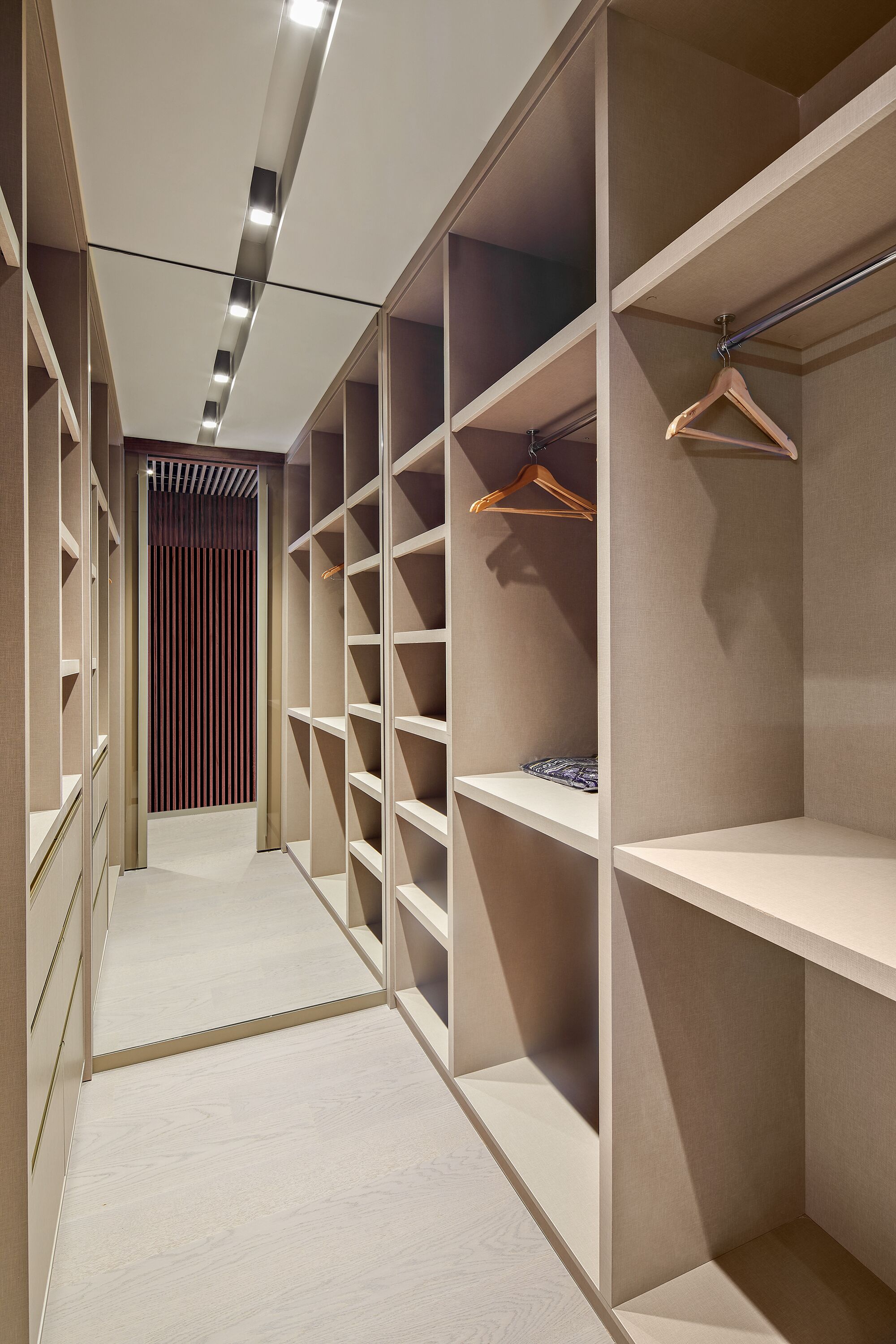 A modern walk-in closet with multiple shelves and hanging space, featuring a clean, minimalist design.