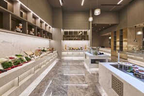 A modern kitchen with marble countertops, built-in shelves, and pendant lighting.