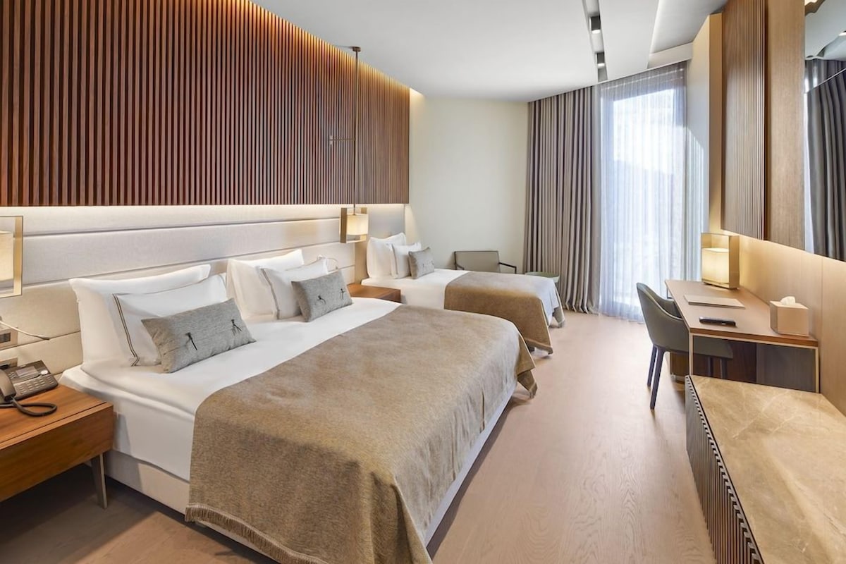 A hotel room with a large bed, a desk, and a chair.