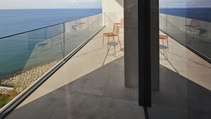A modern balcony with a clear view of the ocean, featuring a glass railing and several chairs. - Ricosta Hotel (Rize)