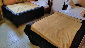 Two single beds with mosquito nets, a tiled floor, and a window with curtains.