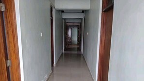 A long, narrow hallway with wooden doors on either side and a tiled floor.