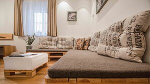 Een gezellige woonkamer met een houten bank, een beklede bank en een kleine tafel met een plant.