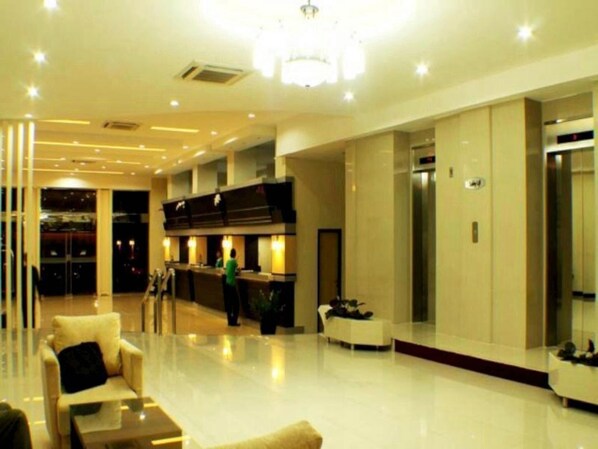 A hotel lobby with a reception desk, seating area, and elevators.