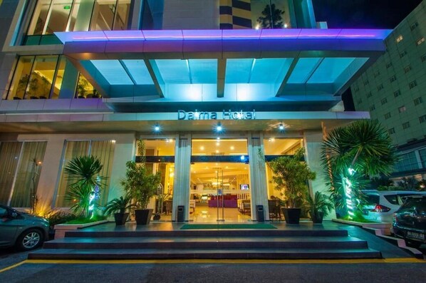 Una entrada de hotel moderna con fachada de vidrio, un letrero que dice 'Darma Hotel' y un área de acceso cubierta.