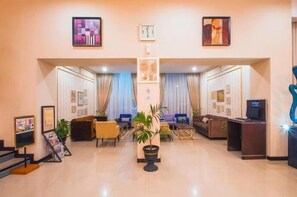 A hotel lobby with a reception desk, seating area, and artwork on the walls.
