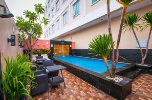 Una piscina rodeada de plantas y muebles de exterior.