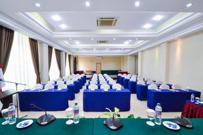 A conference room with rows of tables, microphones, and water bottles. - Daima Hotel (Padang)