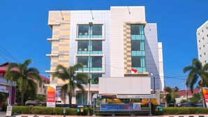 A multi-story building with a modern architectural design, featuring large windows and a prominent entrance. - Daima Hotel (Padang)