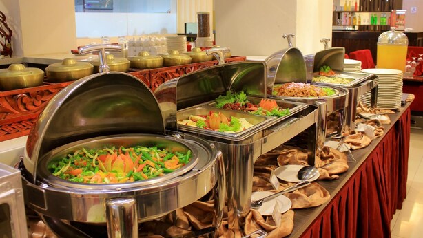 A buffet with various food items and utensils. - Daima Hotel (Padang)
