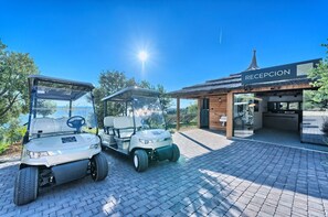 Deux voiturettes de golf sont garées devant un bâtiment sur lequel on peut lire l’inscription « RÉCEPTION ».