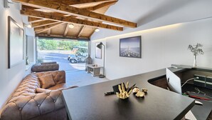 Een modern interieur met een leren bank, een donkere tafel met een decoratief object, en uitzicht op een garage met een voertuig.