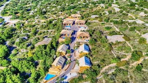 An aerial view of a resort with multiple buildings, a winding road, and a swimming pool.