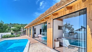 Una vila moderna amb piscina, façana de fusta i grans portes de vidre.