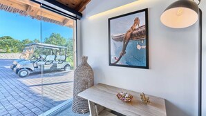 Habitació amb una finestra gran, un quadre emmarcat, una panxa de fusta i una taula amb objectes decoratius.