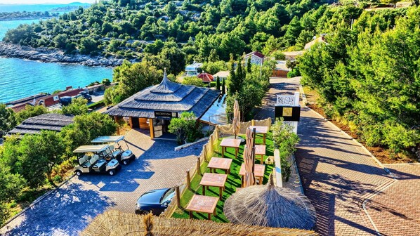 A coastal resort with a reception area, outdoor seating, and a view of the sea.