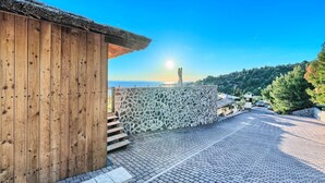 A wooden building with a stone wall and a cobblestone street leading to a scenic overlook. - Luxury Glamp New Horizons V (Murter)