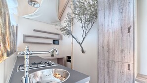 A modern kitchen with a stainless steel sink, a gas stove, and a wooden cabinet. - Luxury Glamp New Horizons II (Murter)