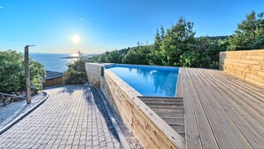 A wooden deck with a swimming pool, a stone pathway, and a view of the sea. - Luxury Glamp New Horizons II (Murter)