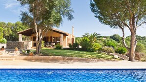 Une maison avec une piscine, entourée d’arbres et de verdure.