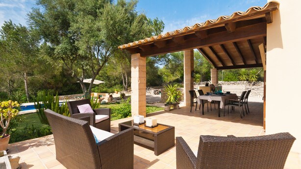 Une terrasse extérieure aménagée avec des meubles en osier, une piscine et une pergola.