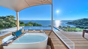 A luxurious outdoor hot tub area with a view of the sea, wooden deck, and a pergola providing shade. - Luxury Glamp New Horizons I (Murter)