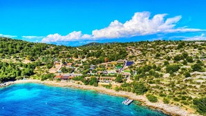 A coastal village with houses, a beach, and a boat. - Luxury Glamp New Horizons I (Murter)