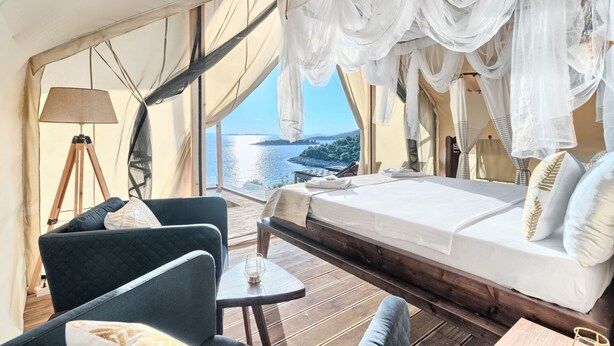 A tent-style room with a bed, a chair, a table, and a lamp. - Luxury Glamp New Horizons I (Murter)