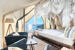 A tent-style room with a bed, a chair, a table, and a lamp.
