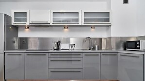 A modern kitchen with grey cabinets, stainless steel appliances, and a microwave.