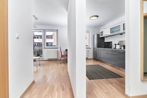 Un appartement moderne doté d’une cuisine, d’un coin repas et offrant une vue sur les immeubles.