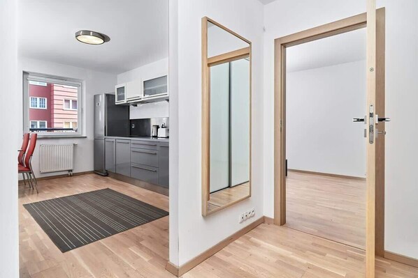 A modern kitchen with grey cabinets, a stainless steel refrigerator, and a window with a view of a red building.