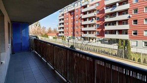 A balcony with a view of a red building with multiple balconies and windows.