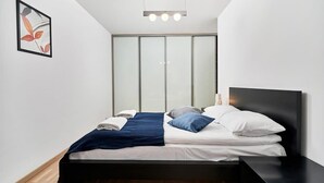 A modern bedroom with a bed, bedside tables, a bedside lamp, and a framed picture on the wall.