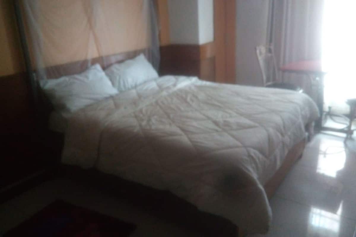 A bed with a canopy, a wooden headboard, and a bedside table with a lamp.