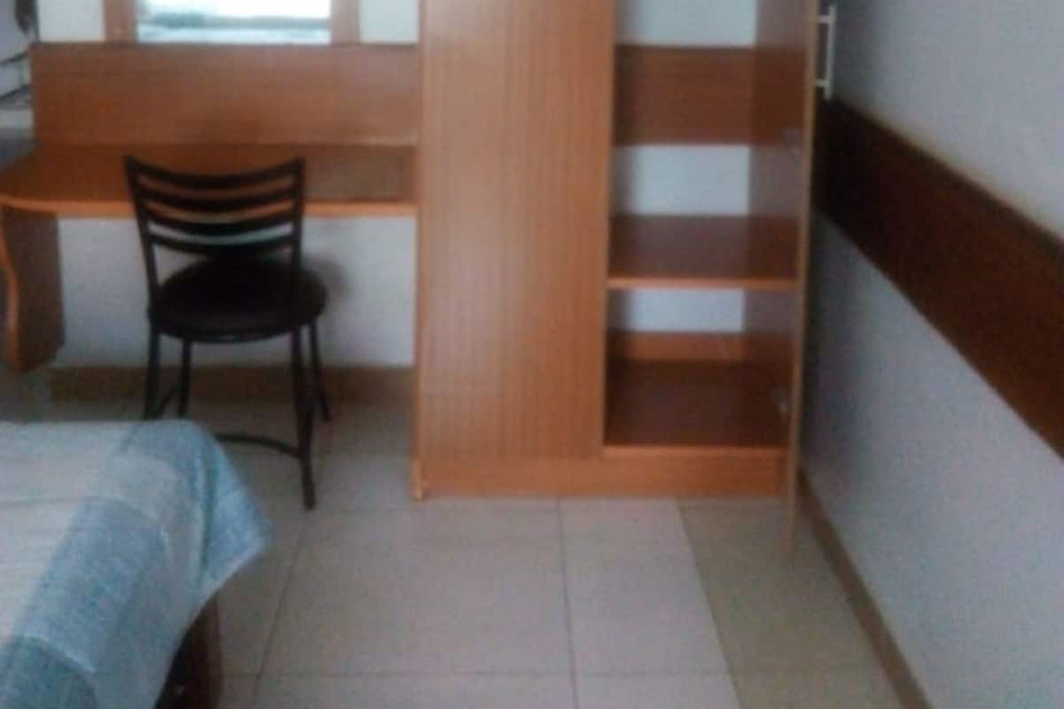 A bedroom with a bed, a desk, a chair, a wardrobe, and a mirror.