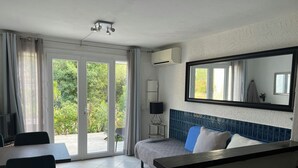Hotelkamer met een bed, een bureau, een stoel, een televisie en een groot raam met uitzicht op groen.