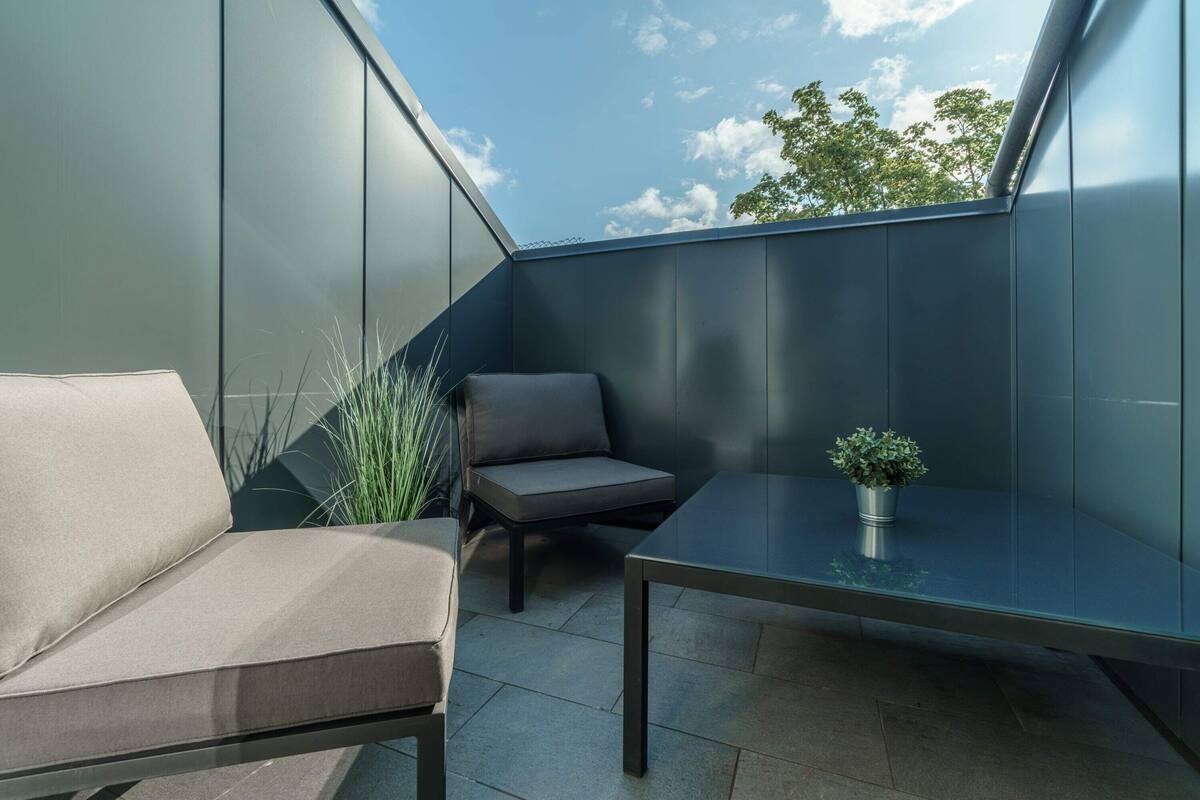 A modern balcony with a sofa, a small table, and a potted plant.