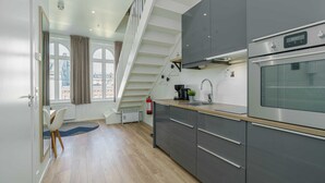 Una cocina moderna con armarios grises, un horno de acero inoxidable y una encimera de madera.