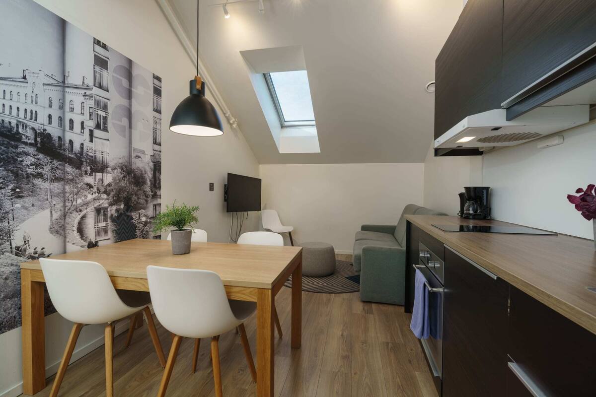 A compact living space with a dining area, kitchenette, and a large window.