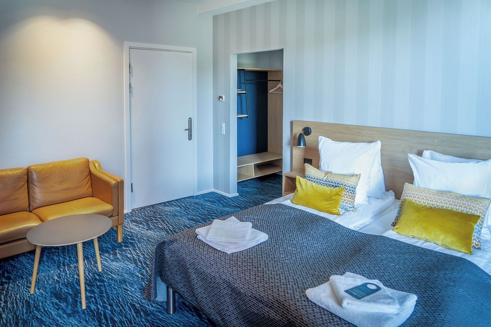 A hotel room with a bed, a sofa, a small table, and a wardrobe.