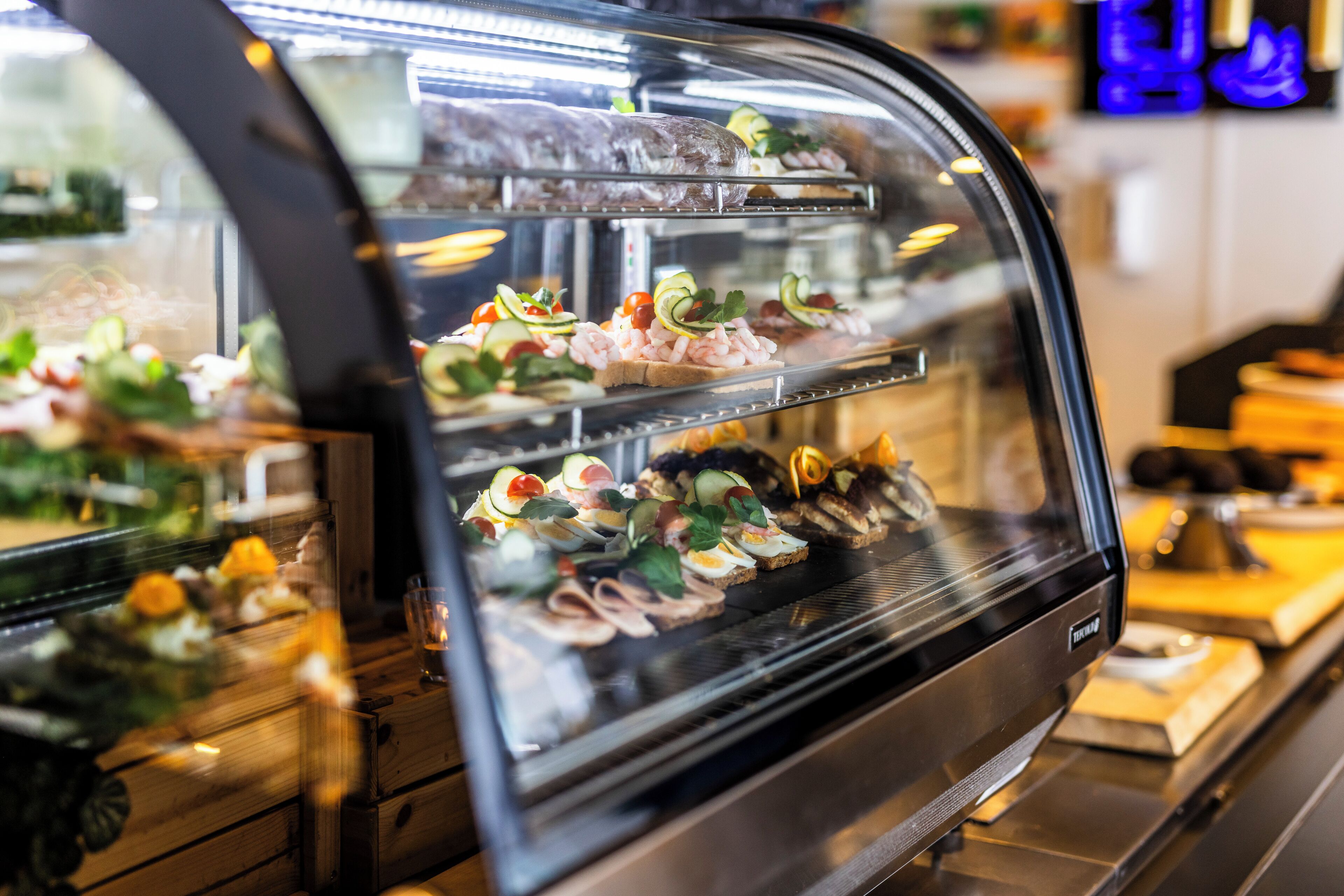 Una vitrina con diversos alimentos, como sándwiches y aperitivos.