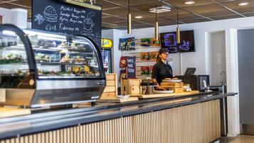 A modern cafe interior with a counter, menu board, and digital menu display.