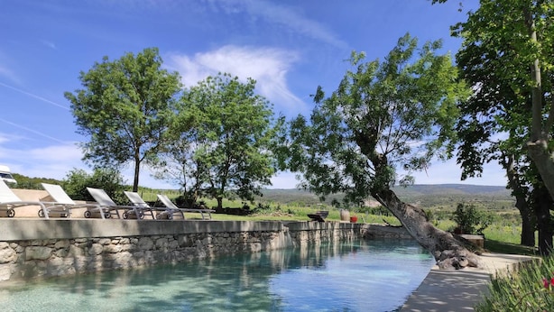 Uma piscina cristalina com espreguiçadeiras e uma parede de pedra.