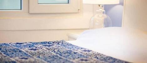 Una habitación de hotel con cama, mesita de noche, lámpara y ventana.