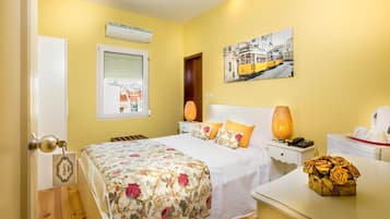 A bedroom with a bed, bedside table, lamp, and a painting on the wall.